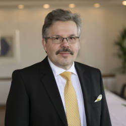 Mikael Knip tummassa puvussa, asusteinaan keltainen solmio ja valkoinen kauluspaita.
